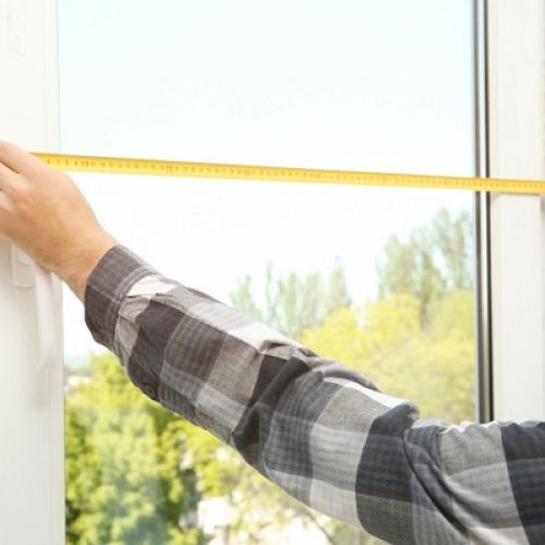 Homme en chemise prenant les dimensions d'une fenêtre