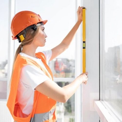 Femme en tenue de chantier prenant les mesures d'une fenêtre